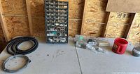 Overall lot showing organizer cabinet, coiled tubing, wire, plastic boxes, red container, glass jar