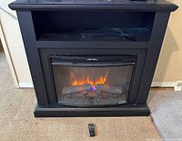 Front view of black Spectrafire electric fireplace mantel showing open shelf and lit firebox