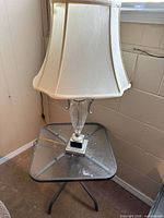 Lamp with shade on glass-top side table, full view