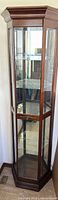 Full view of closed curio cabinet showing wood frame, glass door, side panels, crown top