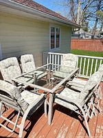 Full patio set showing glass table and six cushioned chairs