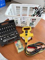 Lot overview showing basket of tools, Husky socket set, measuring tape, booster cables and padlock