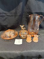 All five pink depression glass pieces displayed: pitcher, butter dish, candy dish with deer lid, two frosted candlesticks