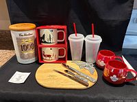 All items grouped: canister, boxed mugs, red mugs, cold cups, cheese board, knives