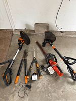 Full lot showing two Worx trimmers, Black & Decker hedge trimmer, Fiskars lopper and shears, chargers and battery