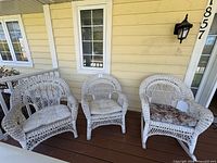 Three white wicker chairs on porch