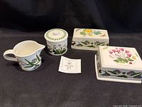 Group view of cream pitcher, sugar bowl with lid, and two butter dish lids