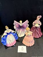 Group shot of four Royal Doulton figurines on black background