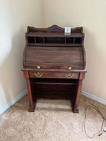 Full frontal view of roll-top secretary desk, drawer, turned legs, power cord visible