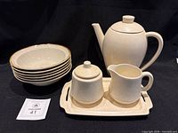 group view of all ten beige speckled stoneware pieces