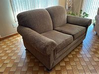 Front angled view of loveseat showing upholstery, arms, cushions, pillows, feet