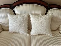 Front view of both lace pillows on striped loveseat