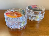 Both round trinket boxes with floral lids and acrylic gems inside