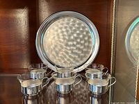 Set of six cups and round tray displayed upright