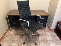 Front view of black high-back office chair on chrome base in front of desk