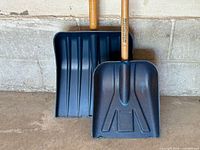 Front view of both blue plastic snow shovels showing blade designs and size difference
