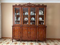 Full front view of complete two-piece cabinet showing wood finish, glass doors, carved details