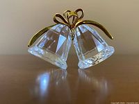 Front view of clear crystal double bells joined by gold-plated bow