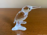 Side view of faceted clear crystal kingfisher on frosted branch