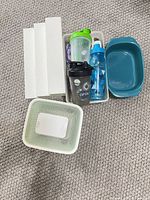 Group of storage containers, shaker cups in bin, baking dish, white lids