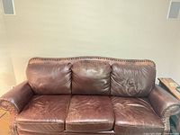 Front view of three-seat brown leather sofa