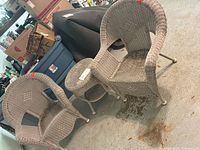 Two gray-tan wicker chairs with matching round side table showing wear