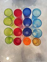 Top-down view of all 16 colored tumblers arranged in four rows