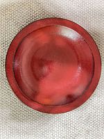 Front view of red ceramic charger showing glaze and rim