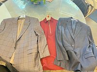 Overall lot: two plaid blazers and red quarter-zip sweater on table