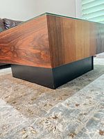 Corner view showing wood veneer sides and black plinth base