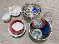 Full lot overview showing stainless bowls, glass containers, ceramic plates and bowls