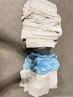 Stack of assorted white, gray and light blue folded queen bedding pieces