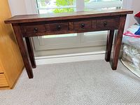 Front view of solid wood console table showing four drawers and overall design