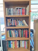 Front view of five-shelf oak finish bookcase filled with books