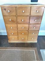 Front view showing all 15 drawers, white knobs, natural pine finish