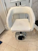 Front view of white faux leather swivel counter stool showing seat, arms and chrome base