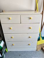 Front view showing five drawers, yellow knobs, wear on surfaces