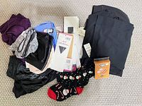 Assorted women’s clothing items, hosiery packages, socks and boxed accessory displayed on carpet