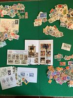 Overall view of souvenir sheets and multiple piles of loose stamps on green surface