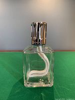Front view of clear square Lampe Berger lamp showing chrome cap and wick