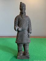 Full view of standing terracotta warrior on green surface