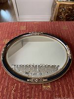 Front view of complete mirror on table showing frame colors and ornament