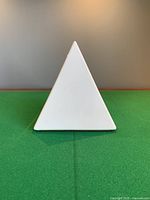Front view of white ceramic pyramid on green surface