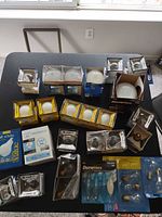 Table with multiple unopened bulb packs from Philips, Westinghouse, ETi plus boxed Sylvania flood bulb