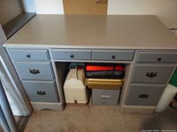 Front view of painted wooden desk showing seven drawers and hardware