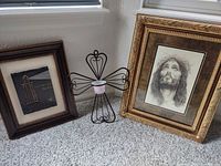 Group shot of two framed artworks and metal cross candle holder