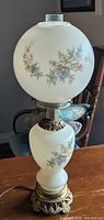 Full view of assembled lamp showing globe, base and floral design
