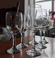 Front angled view of all six clear stemmed wine glasses on tabletop