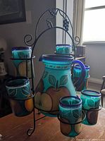 Front view of pitcher and six glasses in iron stand