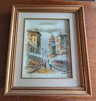 Full view of framed painting showing street scene and frame style